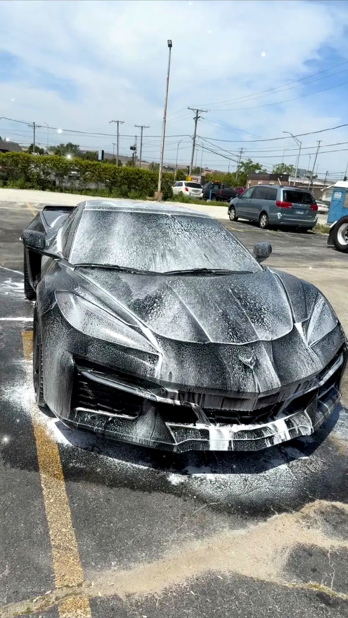 Black Corvette C8 covered in thick snow foam during a mobile wash